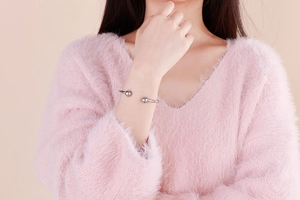 Close-up of minimalist silver stainless steel open bangle with bead details on a model