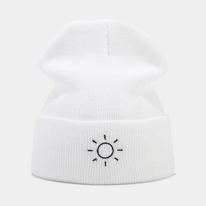Close-up of white ribbed knit beanie featuring minimalist black sun embroidery detail