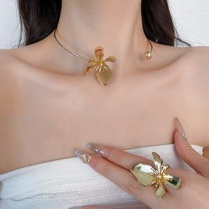 Detailed view of golden flower necklace and matching ring on model for a chic look