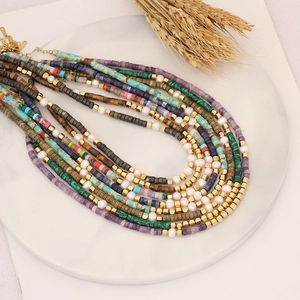 Close-up of colorful gemstone and pearl beaded necklaces displayed on a white plate