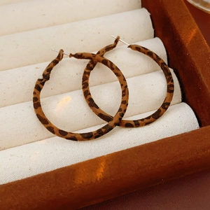 Close-up of large hoop earrings with leopard print velvet fabric on a jewelry roll