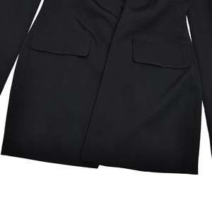 Detailed close-up of the black blazer dress showing hemline and flap pocket texture