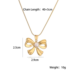 Detail view of gold-plated bow necklace with dimensions 2.5cm by 2.9cm and pearl accent