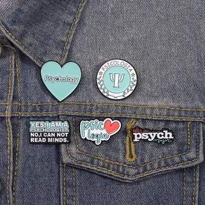 Detailed set of psychology enamel pins with heart and brain motifs on denim jacket