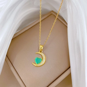 Elegant gold crescent moon necklace with green heart pendant and sparkling crystals
