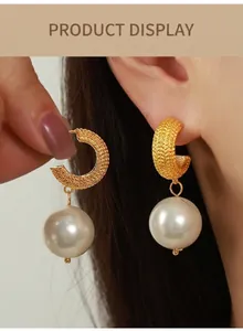 Close-up of gold wheat-textured C-shape earrings with a large white pearl pendant