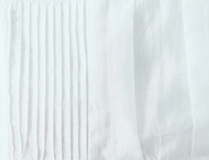 Detailed macro view of white pleated fabric texture with vertical folds and sheer finish