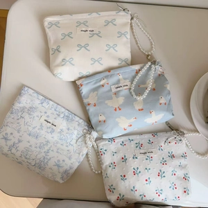 Close-up of four floral cotton mini bags with pearl chains and silver zippers in blue and white