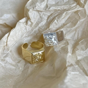 Lava texture silver and gold signet rings with adjustable open band on paper background