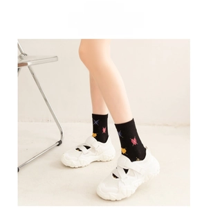 Close-up of black cotton mid-calf socks with colorful heart patterns and ribbed cuffs