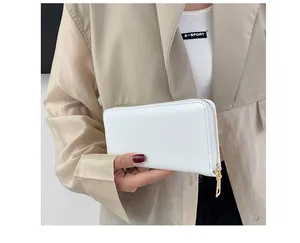 Detail einer weißen Leder-Geldbörse mit Gold-Reißverschluss, von Model in Beige gehalten