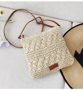 Detail of hand-woven paper rope crossbody bag featuring a brown PU leather strap and patch