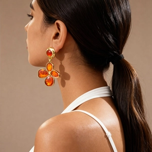 Close-up of vintage golden flower earrings with orange resin on model for retro style