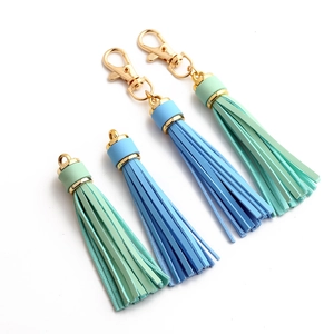 Detail of leather tassel keychains in mint green and sky blue with gold metal lobster clasps
