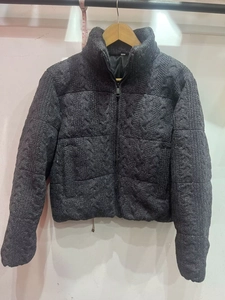 Detail of dark grey chunky knit texture on a hooded puffer jacket with cable weave
