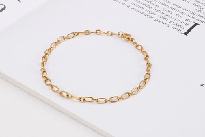 Detailed view of a gold oval link chain bracelet resting on an open book page