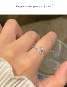 Bague en argent en forme de H avec oxydes de zirconium portée tenant un verre