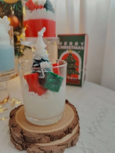 Detail of Christmas scented candle with wax sock and gift box on wood base