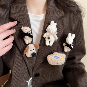 Cute flocked animal brooches with bows pinned on a classic brown herringbone blazer lapel