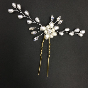 Handmade bridal hair pin with gold metal flowers, pearls, and crystals on black background