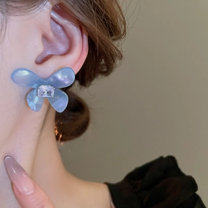Orecchini a farfalla in acrilico blu con zircone indossati da una modella elegante
