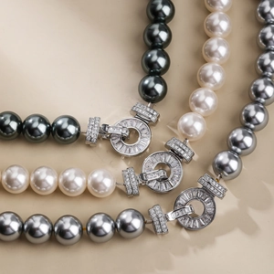 Macro detail of pearl necklaces in black, white, and grey with zircon geometric clasps