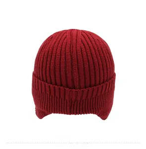 Detail view of the back of a thick knit beanie with earflaps in deep red winter fabric