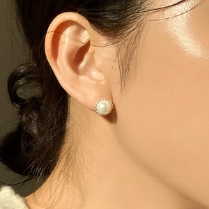 Classic 925 sterling silver pearl earrings with gold beaded edges on a model's ear