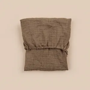 Detail of dark coffee double-layer cotton gauze fitted sheet with elastic band texture
