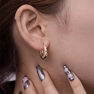 Close-up of a gold croissant twisted hoop earring worn by a model for a stylish look