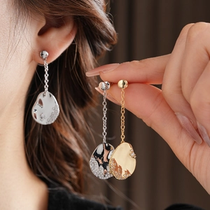 Vue macro de boucles d'oreilles pendantes asymétriques plaquées or 18 carats