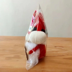 Close-up of a Christmas gnome plush with red knit hat and white beard in clear packaging