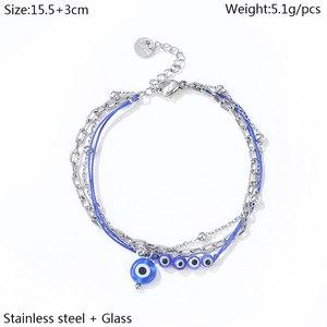 Detail of layered stainless steel evil eye bracelet with blue woven rope and glass beads