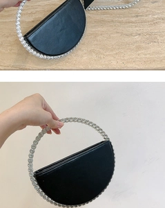 Detail view of a black semi-circular evening clutch bag featuring a sparkling rhinestone handle