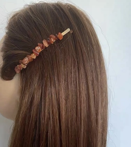 Detail of red agate crystal stone hair clip worn on long brown hair with gold base