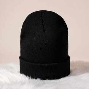 Gros plan d'un bonnet en maille côtelée noire avec bord replié sur peluche blanche douce