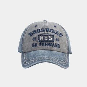 Detail of washed denim baseball cap featuring embroidery and contrast stitching on the brim