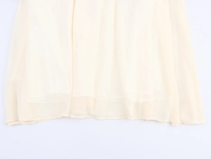 Detailed view of light yellow chiffon dress hem with smooth texture and soft pleats