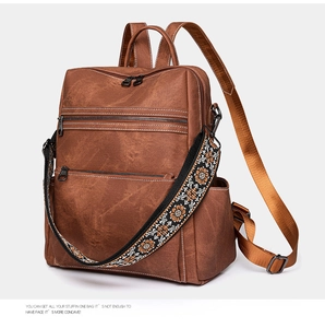 Detail of vintage brown leather backpack with embroidered strap and zipper pockets