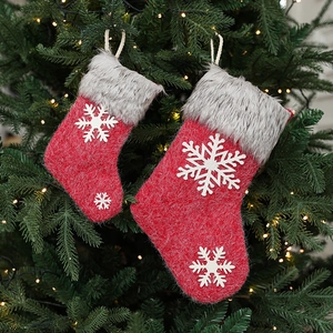 Set of two red felt Christmas stockings with snowflake patches on a festive pine tree
