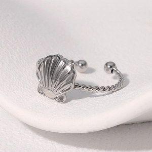 Detalle macro de anillo de concha plateada con banda trenzada y diseño ajustable