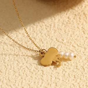 Macro view of 18K gold plated elephant pendant necklace with three white pearls detail
