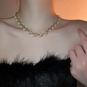 Close-up of gold leaf necklace with white pearls and small diamonds on a model's neck