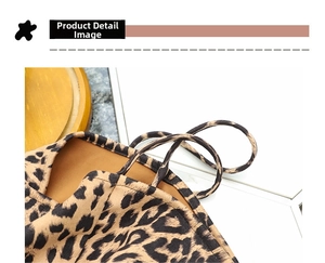 Close-up of leopard print canvas bag straps and reinforced stitching on texture