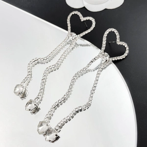 Détail de boucles d'oreilles cœur en strass avec pampilles cristal sur miroir