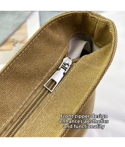 Close-up of thick khaki canvas texture and silver metal zipper on large shoulder bag