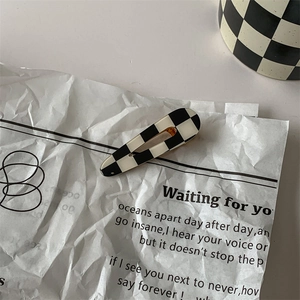 Artistic detail of a black and white checkered hair clip on vintage paper with poetry