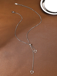 Detail of silver heart lariat necklace with adjustable slider on textured fabric