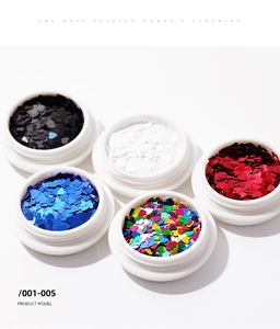 Top-down shot of five colorful heart-shaped nail sequins in white storage jars