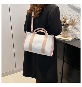 Rear view of a model wearing the white canvas tote bag with pink straps in a minimalist room
